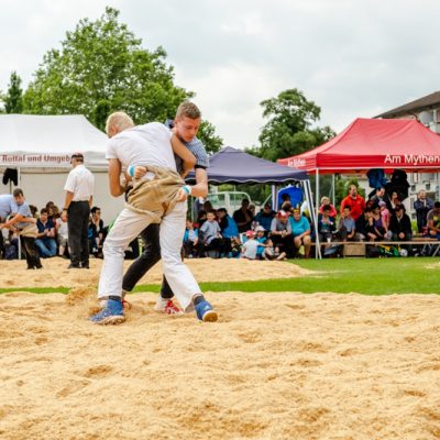 Two boys practising Schwingen in a sawdust ring at a Swiss wrestling festival